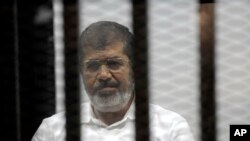 FILE - Egypt's ousted Islamist President Mohamed Morsi sits in the defendant cage in the Police Academy courthouse during a court hearing on charges of inciting the murder of his opponents, in Cairo, Egypt, Nov. 3, 2014.