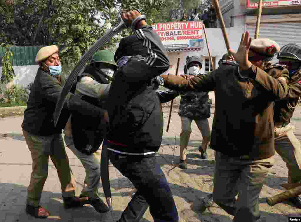 A man uses his sword against a policeman during a clash between protesting farmers and a group of people shouting anti-farmer expressions, at the site of a protest against farm laws at Singhu border near New Delhi, India.