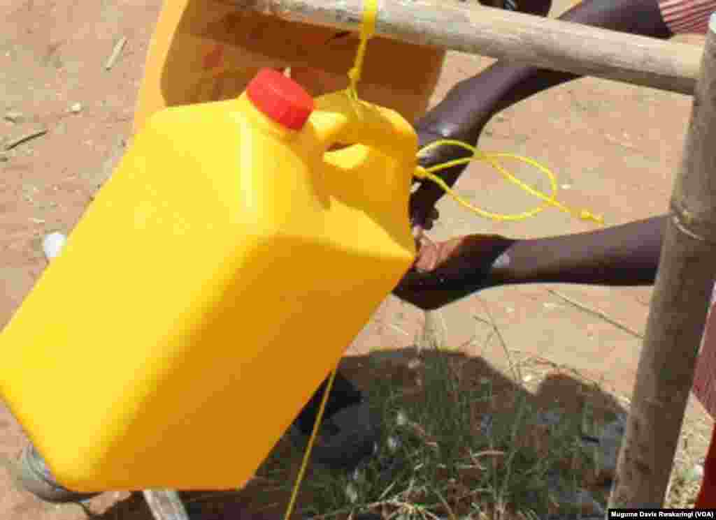 South Sudanese kids wash their hands using water from a jerry can.