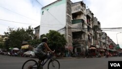 A cyclist rides pass the northern wall of Phnom Penh’s White Building where a painted mural of a woman’s portrait was white-washed controversially by the Phnom Penh Municipality. (Aun Chhengpor/VOA Khmer)