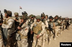 FILE - Iraqi security forces wait for vehicles traveling to Mosul to fight against militants of Islamic State at an Iraqi army base in Camp Taji in Baghdad, Feb. 21, 2016.