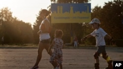 People walk past a sign that reads "Kramatorsk is Ukraine!" painted in colors of Ukrainian national flag, in Kramatorsk, eastern Ukraine, Aug. 9, 2014.