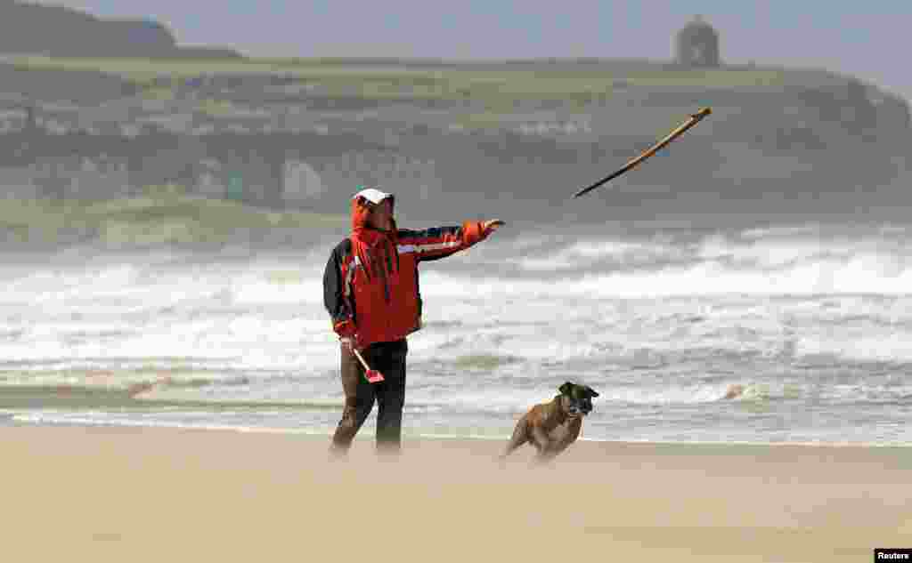 A man walks his dog on Portstewart Strand during heavy winds on the Causeway Coastline, northern Ireland.