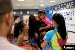 Sana Tahir carries Malaika Noman, 3, as the child arrives in the United States after a federal judge ruled Thursday that President Trump's temporary ban on travelers from six Muslim-majority countries cannot stop grandparents and other relatives of U.S. citizens from entering the country at Washington Dulles International Airport in Dulles, Virginia, July 14, 2017.