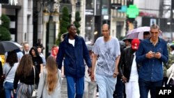 (De gauche à droite) Abdramane Dembele, 2m35 Brahim Takioullah, 2m46 et Arshavir Grigoryan, 2m33, se promènent dans la foule sur l'avenue des Champs-Elysées, à Paris, le 1er juin 2018.