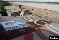 People display portraits of U.S. President Barack Obama on the roof of their houses near Phnom Penh Airport November 14, 2012.