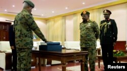 FILE - Defense Minister Awad Mohamed Ahmed Ibn Auf (L) is sworn in as first vice president in front of President Omar al-Bashir during a swearing in ceremony of new officials after Bashir dissolved central and state governments, Khartoum, Sudan, Feb. 24, 2019.