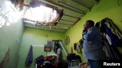 People check the damage after debris from ballistic missiles fired by Yemen's Houthi militia fell onto a house in Riyadh, Saudi Arabia, March 26, 2018. 