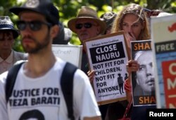 FILE - Protesters react as they hold placards and listen to speakers during a rally in support of refugees in central Sydney, Australia, Oct. 19, 2015.