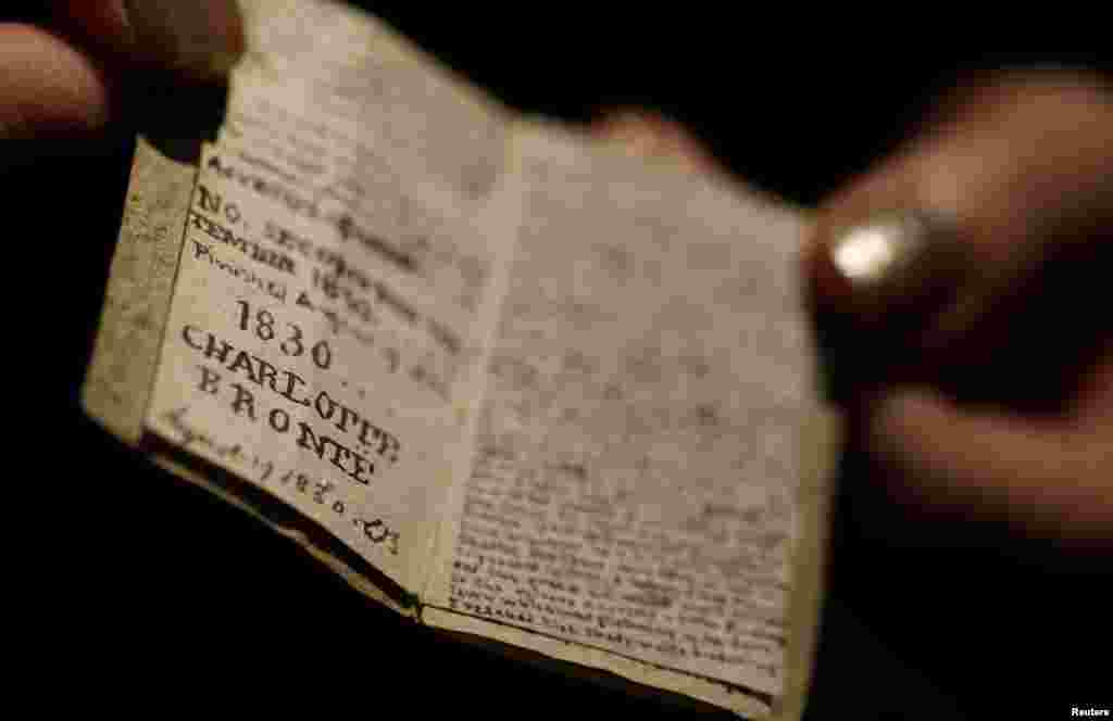 An employee displays the second issue of Young Men's Magazine, a miniature manuscript dated 1830, written by Charlotte Bronte when she was 14 years old, before being put on auction at Drouot auction house in Paris, France.