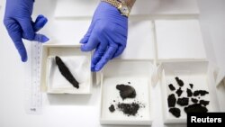 An Israel Antiquities Authority worker displays a scroll (L), found in 1970, along with other findings, that are yet to be analyzed, at the Israel Museum in Jerusalem, July 20, 2015.