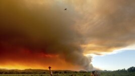 FILE - In this Aug. 20, 2020, file photo, Thomas Henney, left, and Charles Chavira watch a plume spread over Healdsburg, California.
