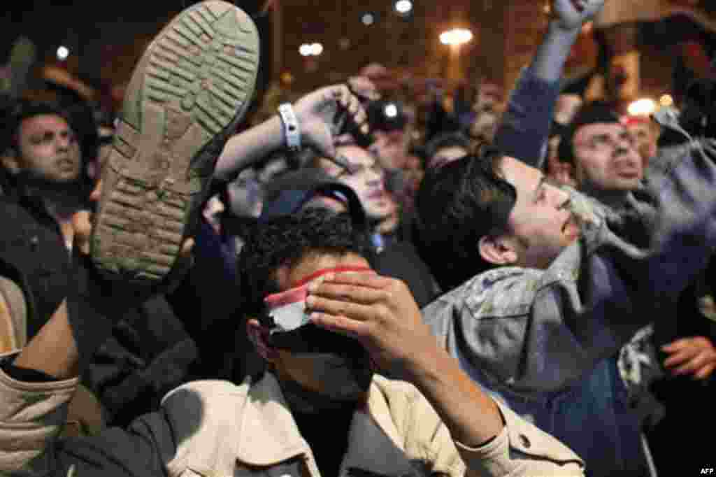 An anti-government protester holds up his shoe as people react as Egyptian President Hosni Mubarak makes a televised statement to his nation in Tahrir Square in downtown Cairo, Egypt Thursday, Feb. 10, 2011. Egyptian President Hosni Mubarak announced he 