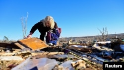 A woman searches through debris near the location in Dawson Springs, Ky., where her mother and aunt were found deceased after tornadoes ripped through several US states