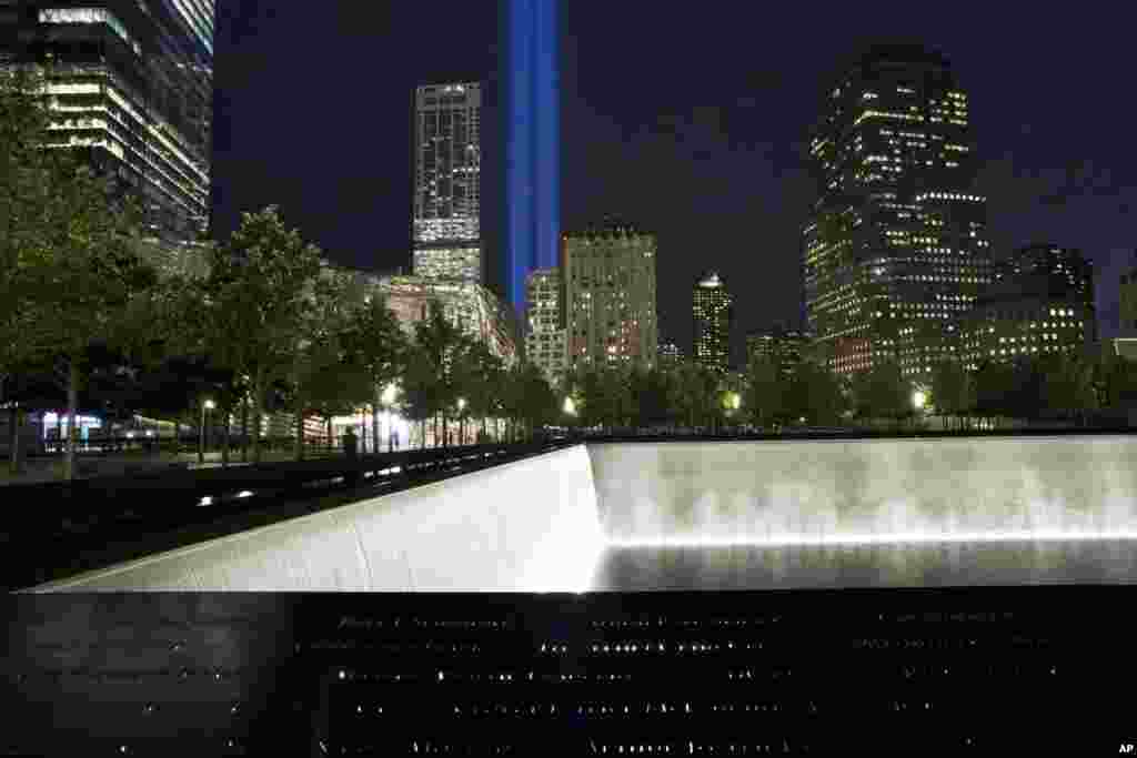 The Tribute in Light rises behind buildings adjacent to the World Trade Center complex and a reflecting pool at the National September 11 Memorial, in New York, Sept. 8, 2014.