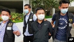 Ryan Law, second from right, Apple Daily's chief editor, is arrested by police officers in Hong Kong Thursday, June 17, 2021. Hong Kong police on Thursday morning arrested the chief editor and four other senior executives of Apple Daily.