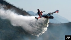 In this photo provided by the Santa Barbara County Fire Department, a Bombardier 415 Super Scooper makes a water drop on hot spots along the hillside east of Gibraltar Road in Santa Barbara, California., Dec. 17, 2017.