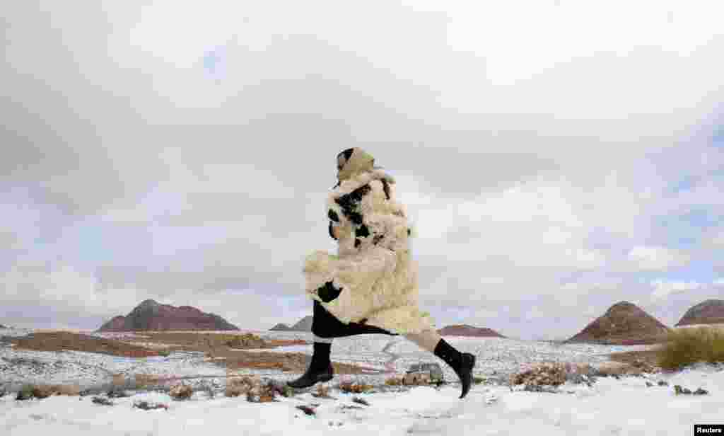 A man runs through snow after a snowstorm in the desert, near Tabuk, 1,500 km (932 miles) from Riyadh, Saudi Arabia. 