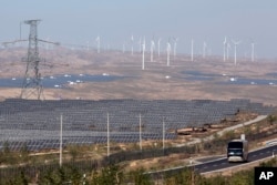 FILE - In this file photo taken Oct. 10, 2015, a bus moves past by solar power and wind power farms in northwestern China's Ningxia Hui region.