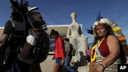 Indians walk past a statue of justice as they protest outside the Supreme Court, in Brasilia, Brazil, Aug. 16, 2017. Brazil's indigenous communities protested as the Supreme Court deliberated on the legality of President Michel Temer's plan to restrict land titles awarded to the communities.