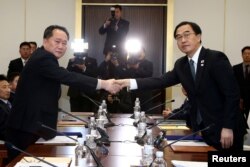 Head of the North Korean delegation, Ri Son Gwon shakes hands with South Korean counterpart Cho Myoung-gyon as they exchange documents after their meeting at the truce village of Panmunjom in the demilitarized zone separating the two Koreas, South Korea, Jan. 9, 2018.