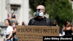 Seorang pengunjuk rasa di Trafalgar Square, London, Inggris, 31 Mei 2020. memegang kertas bertuliskan "Black Live Matters" dalam aksi protes menentang kematian pria Afrika-Amerika George Floyd, di Minneapolis.