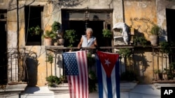 FILE - Javier Yanez stands on his balcony in Old Havana, where he hung U.S. and Cuban flags after learning that the two nations would begin restoring diplomatic ties.