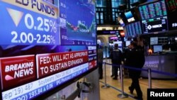 Sebuah layar menampilkan pengumuman suku bunga Federal Reserve AS ketika para pedagang bekerja di lantai New York Stock Exchange (NYSE) di New York, AS, 31 Juli 2019. (Foto: Reuters/Brendan McDermid)