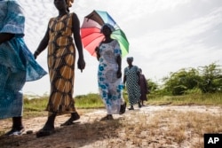 In this photo taken Monday, Oct. 19, 2015, women walk on farmlands that were destroyed by high salt content due to rising sea levels in Saloum Delta, Diamniadio Island in Senegal.