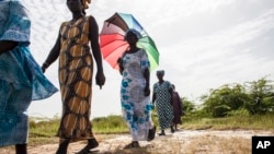 FILE - Women walk on farmlands that were destroyed by high salt content due to rising sea levels in Saloum Delta, Diamniadio Island in Senegal. 