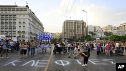 A protester writes graffiti which reads 'Thieves'' outside the Greek Parliament during a peaceful rally for a 15th day, called through a social networking site in Athens, June 8, 2011