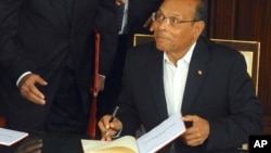 Tunisian President, Moncef Marzouki reacts as he signs the new Constitution in Tunis, Jan. 27, 2014