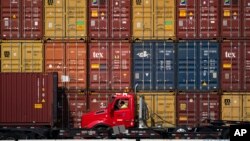 A driver sits in his truck as containers are stacked up in the yards at the Port of Long Beach in Long Beach, Calif., Nov. 17, 2021.