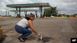 A woman places a candle at the gas station where Candido Rios Vazquez, a reporter for the Diario de Acayucan, was murdered in Hueyapan de Ocampo, Veracruz state, Mexico, Aug. 23, 2017. The National Human Rights Commission said that Rios was the ninth journalist killed this year in Mexico.
