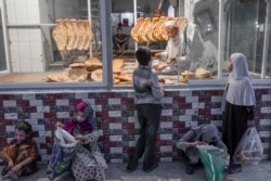 Seorang anak (tengah) menunggu giliran untuk menerima roti gratis di depan sebuah toko di Kabul, Afghanistan, 14 September 2021. (Foto: AFP/Bulent Kilic)