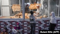 Seorang anak (tengah) tengah menunggu giliran untuk menerima roti gratis di depan sebuah toko di Kabul, Afghanistan, pada 14 September 2021. (Foto: AFP/Bulent Kilic)