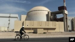 FILE: A bicyclist passes the nuclear power plant just outside Bushehr, Iran, Oct. 26, 2010. 