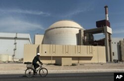 FILE - A bicyclist passes the nuclear power plant just outside Bushehr, Iran, Oct. 26, 2010.