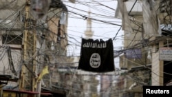 FILE - An Islamic State flag hangs amid electric wires over a street in Ain al-Hilweh Palestinian refugee camp, near the port-city of Sidon, southern Lebanon Jan. 19, 2016.