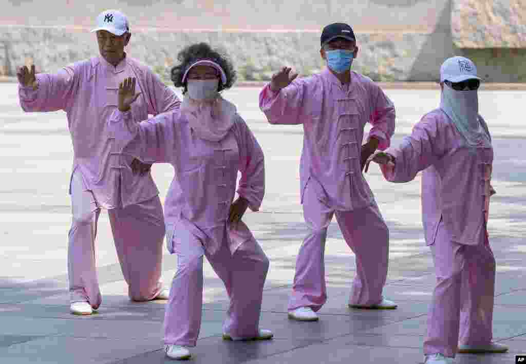 Taiji practitioners, some wearing masks, go through their routine in Beijing.