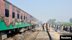 People and rescue workers gather at the place where a fire broke out in a passenger train and destroyed three carriages near the town of Rahim Yar Khan, Pakistan, October 31, 2019. 