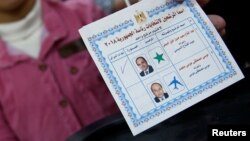 An Egyptian woman shows her ballot paper with a sign for Egypt's President Abdel Fattah el-Sissi before casting her vote during the first day of the presidential election at a polling station in Cairo, Egypt, March 26, 2018.