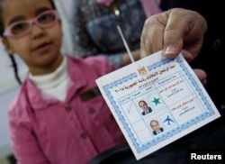 An Egyptian woman shows her ballot paper with a sign for Egypt's President Abdel Fattah el-Sissi before casting her vote during the first day of the presidential election at a polling station in Cairo, Egypt, March 26, 2018.