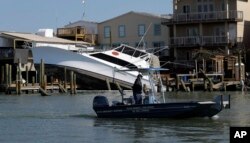 An emergency response boat passes a boat that was displaced by the effects of Hurricane Harvey, in Port Aransas, Texas, Aug. 30, 2017.