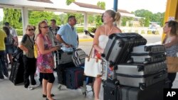 FILE - British tourists queue with their luggage to leave by charter flight from the international airport in Mombasa, Kenya.