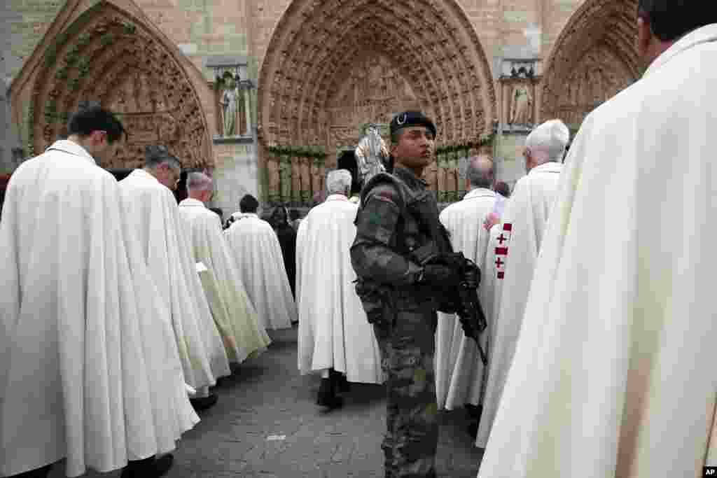 French soldier stands in the middle of clergy men during a catholic procession in front of Notre Dame cathedral as part of the Assumption of Mary celebration in Paris, France.