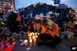 FILE - Tasha Lomoglio, of Dallas, cries after lighting candles at a makeshift memorial in honor of the slain Dallas police officers in front of police headquarters in Dallas, Texas, July 9, 2016.