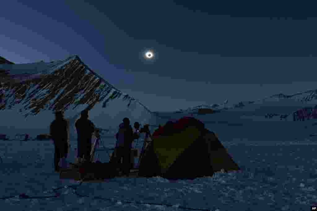 In this photo provided by Imagen de Chile, people view a total solar eclipse from Polar Union Glacier Camp in Antarctica, Dec. 4, 2021.