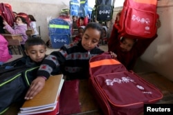 Syrian children carry bags, printed with a UNICEF logo, that they received as aid inside their classroom in Ras al-Ain city, Syria, Feb. 1, 2016.