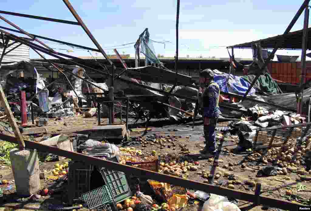 2013年3月19日，一名警察守卫在巴格达市舒拉尔区汽车炸弹袭击现场。